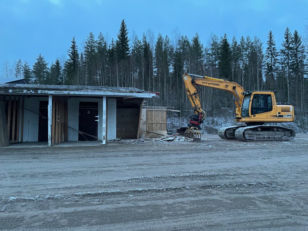 Vanhan valjastuskatoksen purkua kaivinkoneella